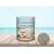Close-up of ceramic mug featuring vibrant seashells and sand.